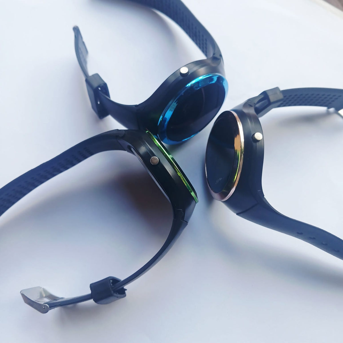 Three round-face watches with black straps and blue, green and gold-coloured face surrounds